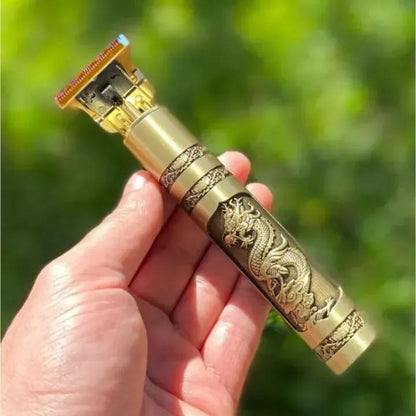 Decorative gold and bronze hair trimmer held in a hand with a blurred green background