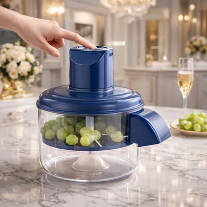 Blue grape juicer on a marble countertop with grapes inside, in a kitchen setting.