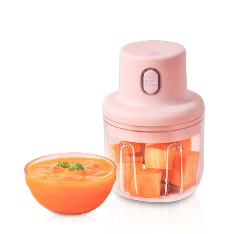 Pink hand juicer with carrot pieces and a bowl of carrot juice on a white background